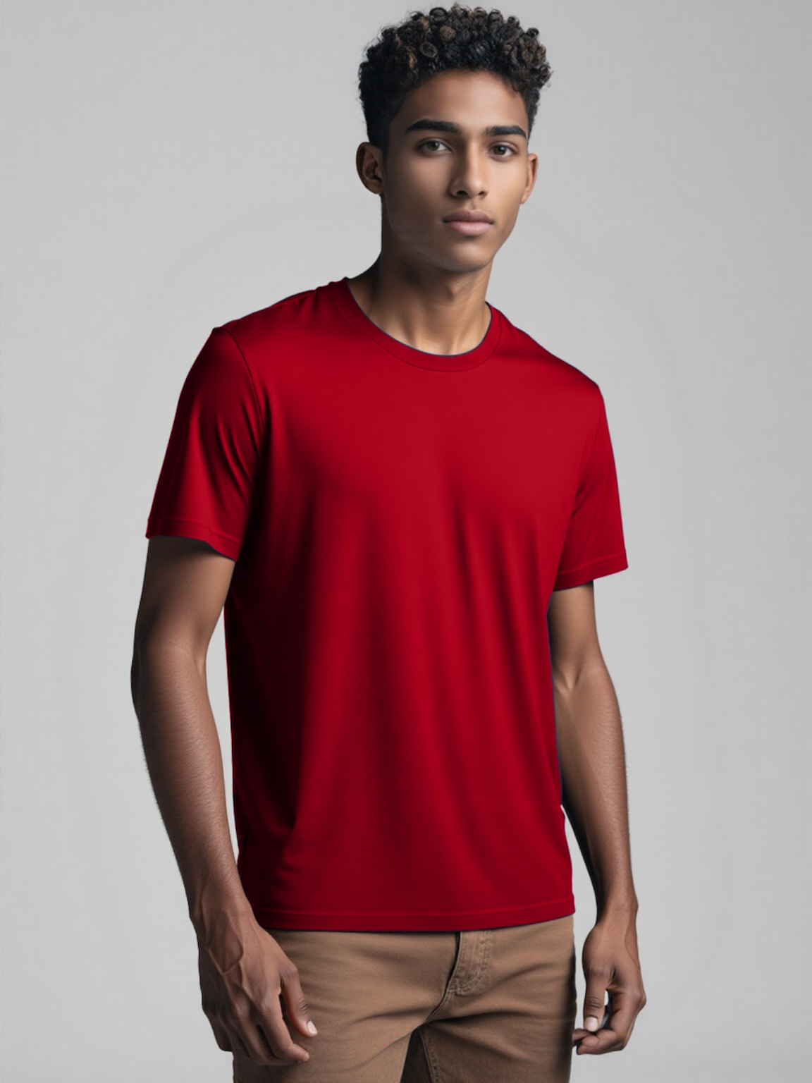 A man wearing a red t-shirt stands confidently, showcasing a casual and relaxed style.