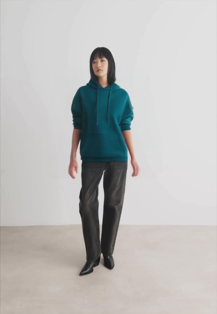 Load video: Woman wearing a teal green pullover hoodie.