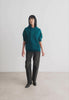 Woman wearing a teal green pullover hoodie.