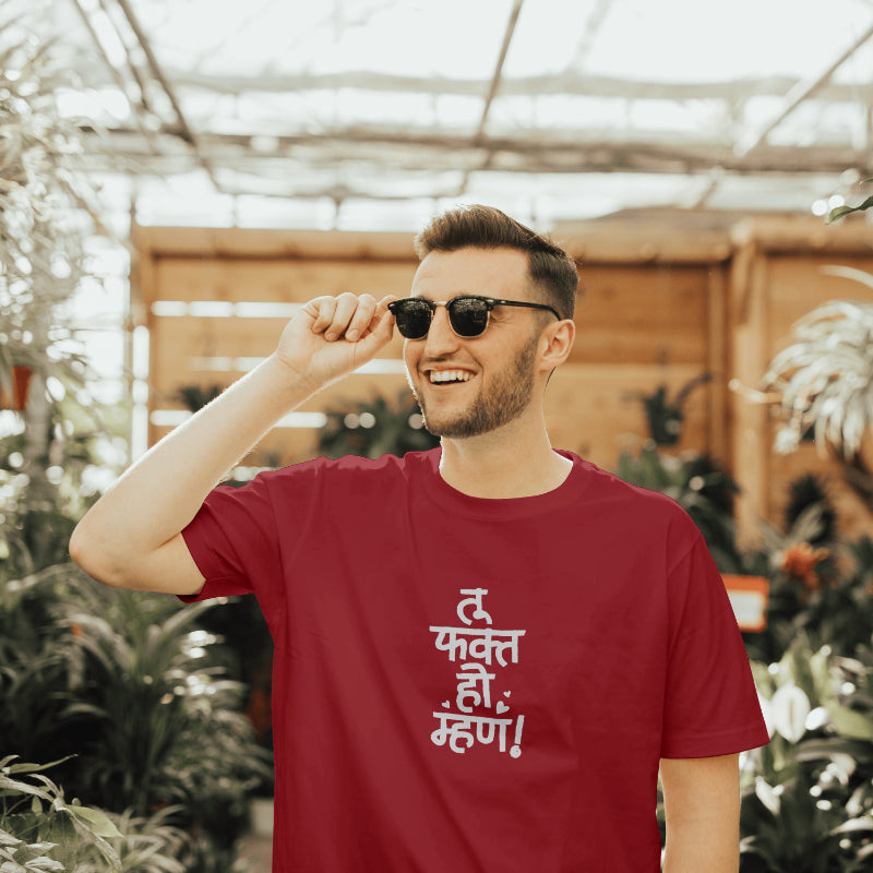 A man wearing sunglasses and a red t-shirt with "tu fakt ho mhan" printed on it, smiling at the camera.